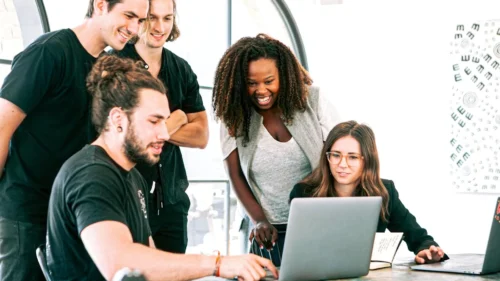 Leasing dla startupów - Grupa młodych osób pracujących wspólnie przy laptopie w biurze.