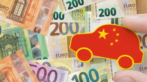 Zabawkowy samochód pomalowany w kolory flagi Chin. W tle widoczne są banknoty.